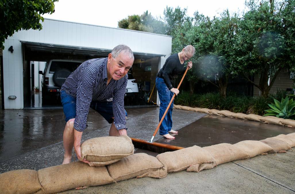 Port Fairy residents Kevin and Annie O'Toole lay sandbags to prevent water running into their house. Picture: Rob Gunstone
