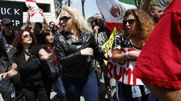 A woman is yelled at and pushed by protesters as she attempts to make her way into the Hyatt Regency during the first day of the California Republican Party Convention. Photo: Leah Millis