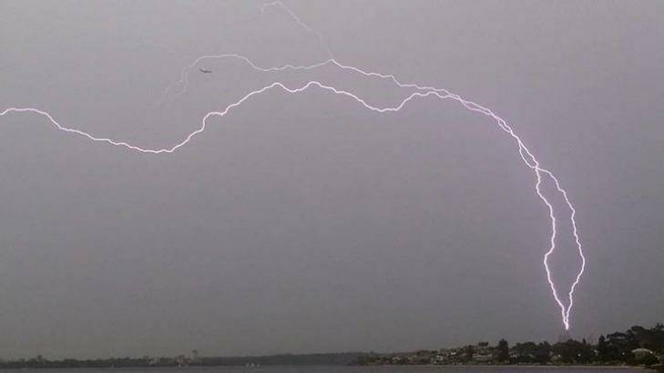 Lightning seems to threaten a plane and the BHP tower. Photo: Perthweatherlive.com