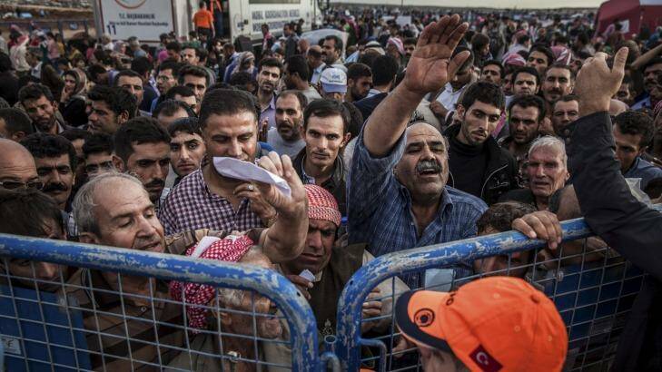 Syrian Kurdish refugees press against a gate as they hope to be allowed into Turkey. Photo: New York Times