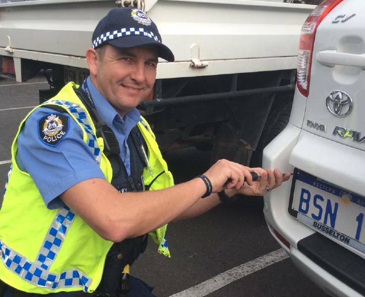 Busselton police constable Richard Penn fits anti theft screws to a residents vehicle.