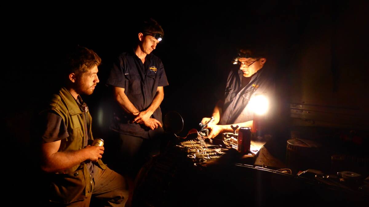 ROAD TO RUIN: Four modern-day explorers tackle the Canning Stock Route, the longest in the world. Here they are taking a late night stop to overhaul a fuel pump. Photo: Supplied.