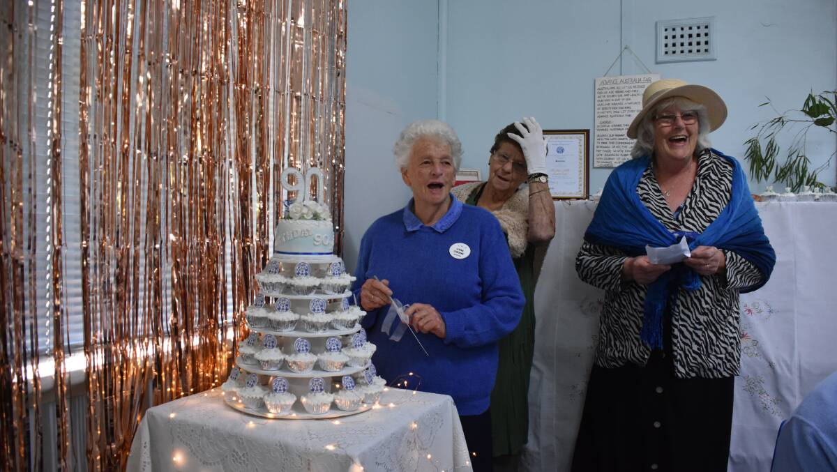 CWA Busselton branch's longest serving member Lorna Osborne cuts the cake made by Mary Fullerton.