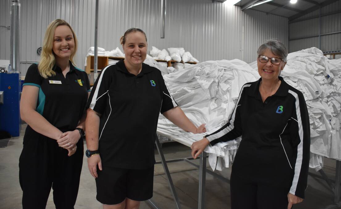 AtWork job coach Kristie O'Conner with Baythe Linen and Laundry worker Catherine Bunter-Howie and general manager Karen Harrison.
