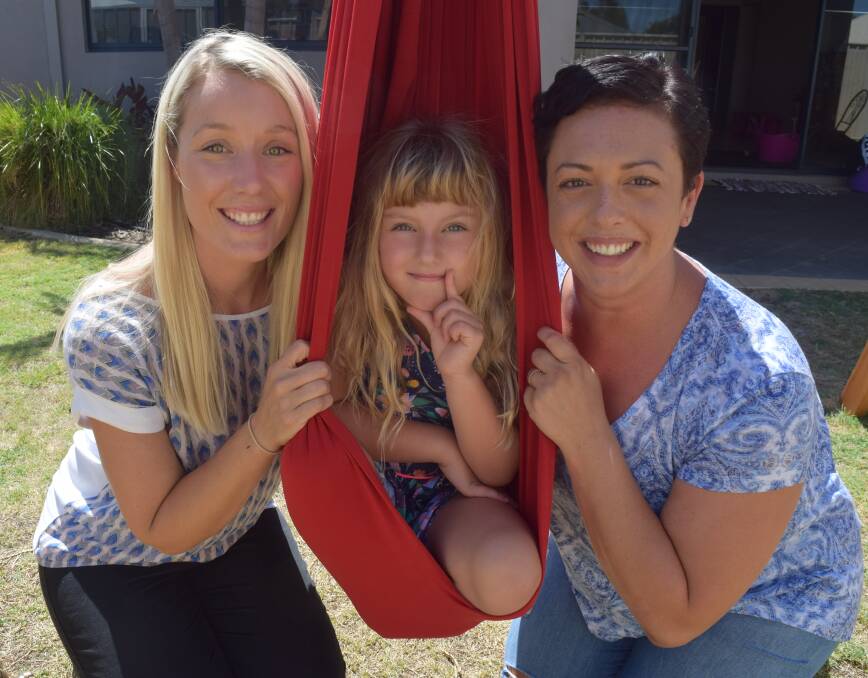 Occupational therapist Steph Gordon, Olivia McDonnell and Jenna McDonnell with sensory hammock provided by Variety WA. Image Sophie Elliott.