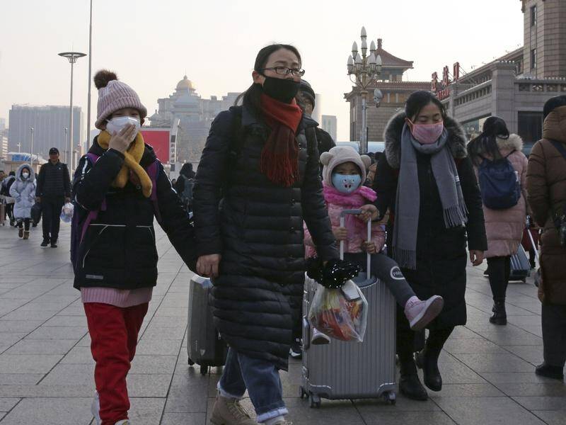 People wearing masks head for Beijing Station amid a new coronavirus outbreak.