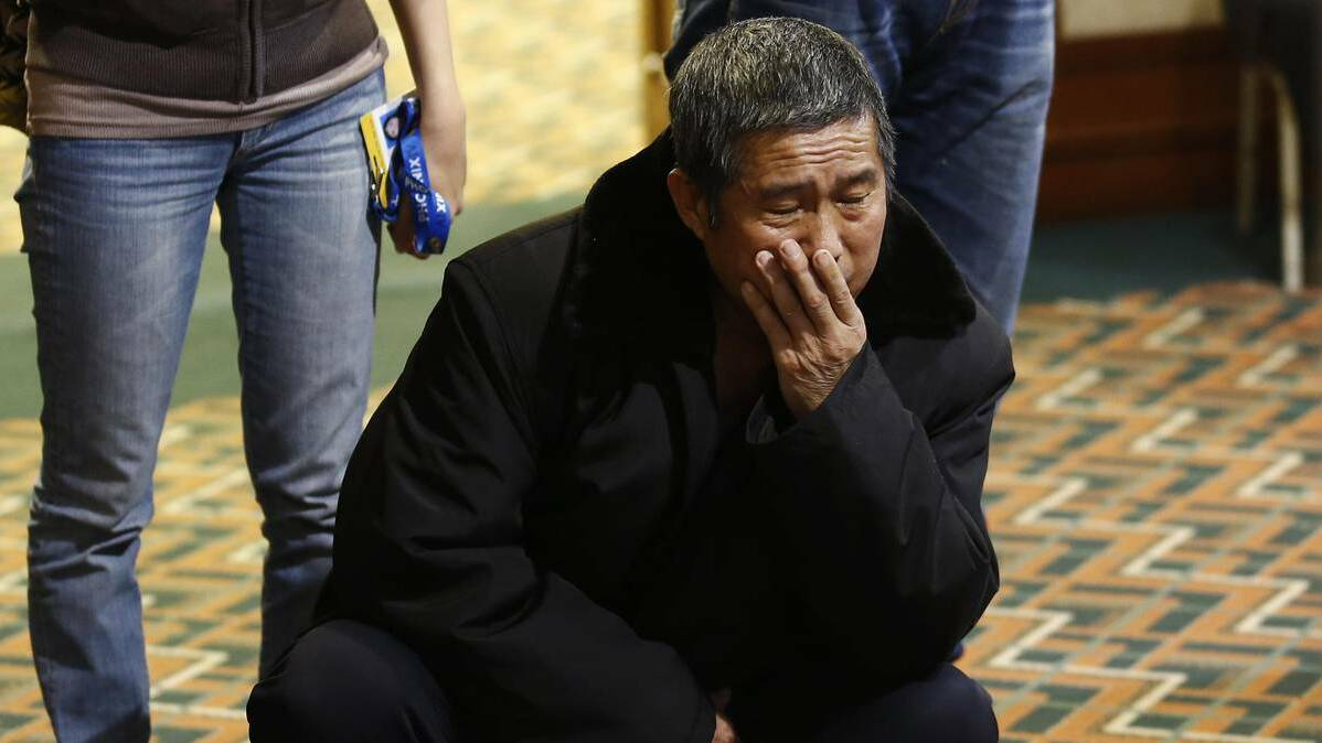 A family member of a passenger onboard the missing Malaysia Airlines flight MH370 reacts as he watches a message board dedicated to the passengers onboard the missing plane at a hotel in Beijing March 20, 2014. Photo: Reuters.