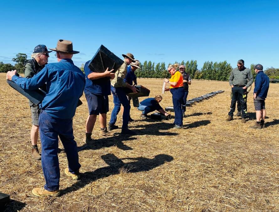 Many hands make light work everyone lends a hand to measure fertiliser caught in trays laid out across a paddock.