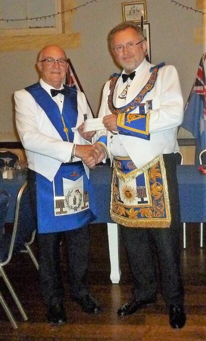Donation: Eric Meaock presents a cheque for $200 to the most worshipful grand master Peter Kirwin. Photo: supplied.