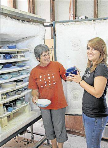 Anna Whiteman and rotary exchange student Andrea Elsener unpack the freshly glazed pots.